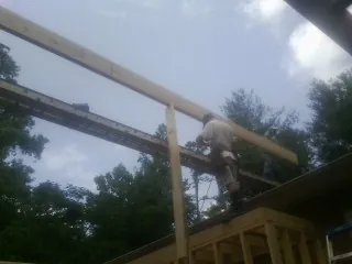 Carpenter setting a ridge beam over a new addition frame — Ice Dam Removal by Roofing Brothers in Clarkdale
