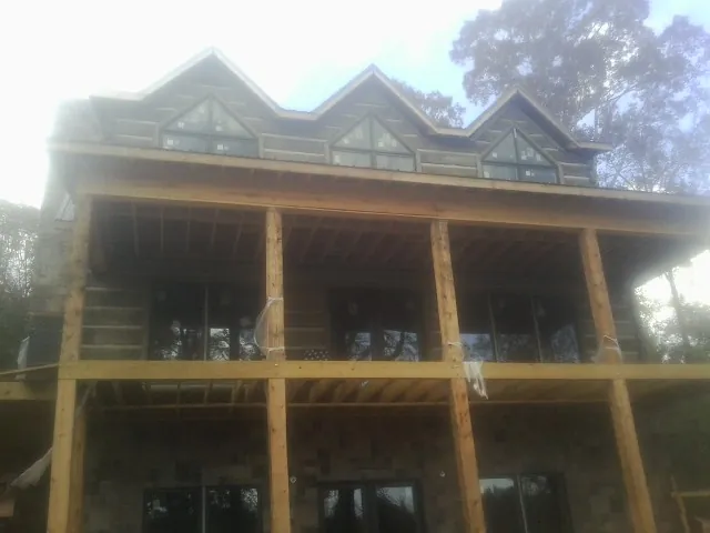 Dormers and porch framing on a large log home under construction — Roof Coating work by our crew in Clarkdale
