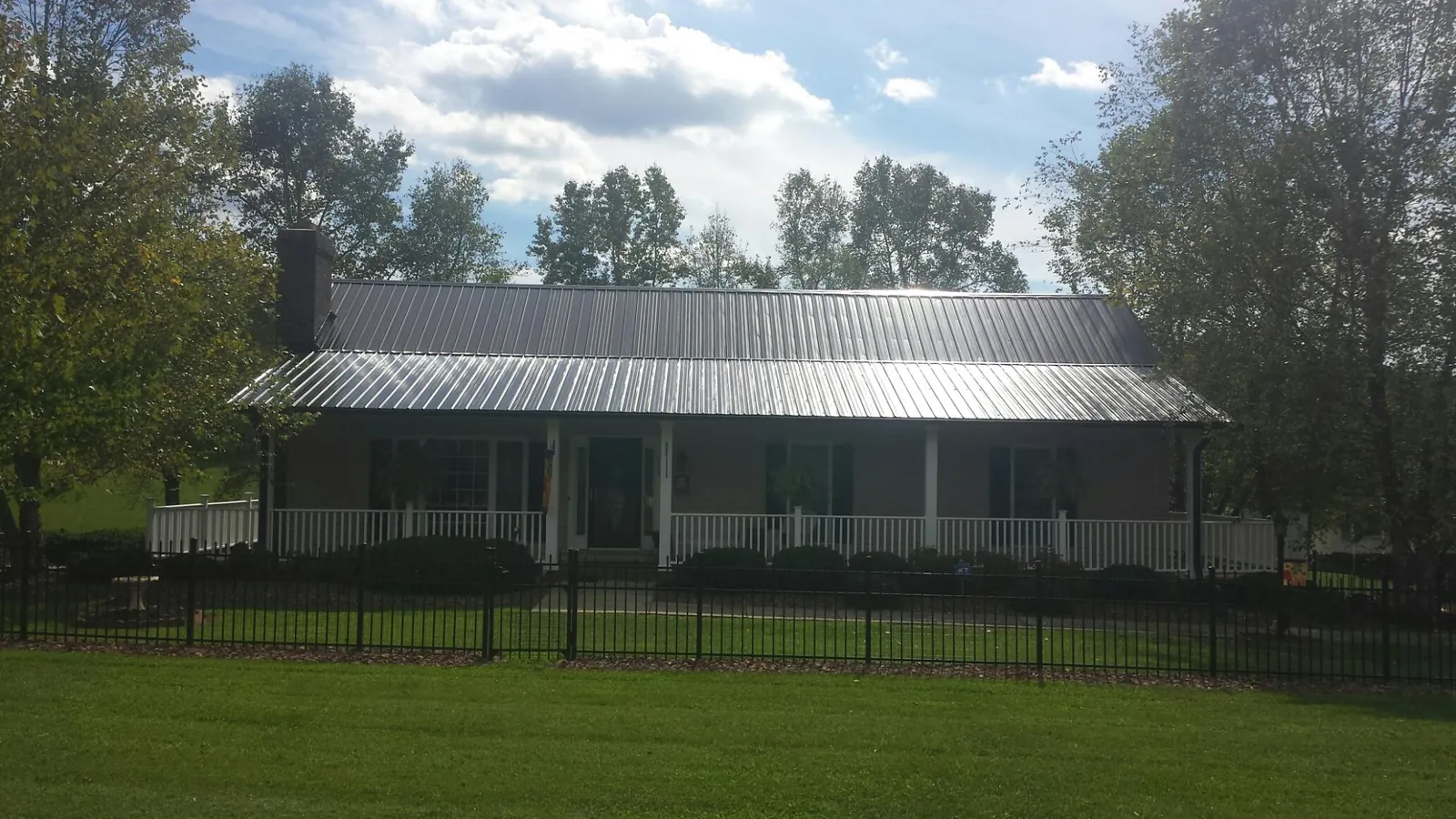 Gray metal roof on a brick ranch with a full width front porch — Gutter Guard Installation work by our crew in Clarkdale